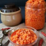 A stack of glass mason jar, glass bowl and cay pot full of carrot, ginger and lemon pickle.