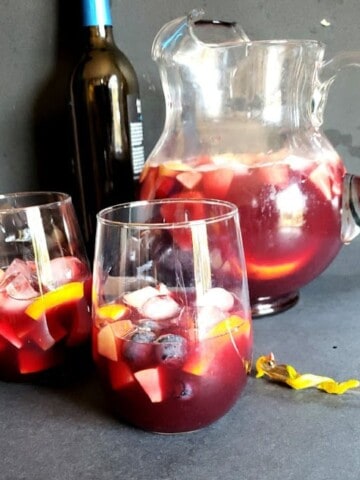 A pitcher and two glasses filled with classic Spanish Red wine Sangria drink.