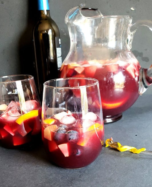 A pitcher and two glasses filled with classic Spanish Red wine Sangria drink. 