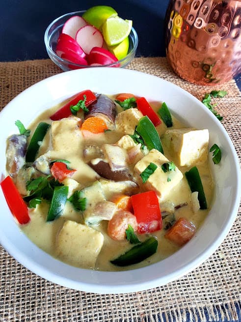 A close up of vegan thai green curry showing creamy velvety texture and colorful crunchy vegetables.