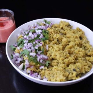 A serving bowl filled with Moong Daal Khichadi served garnished with chopped onions and cilantro.