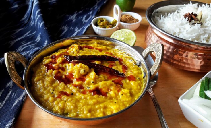 copper container full of spicy lentil curry dahl seasoned with red chili oil.