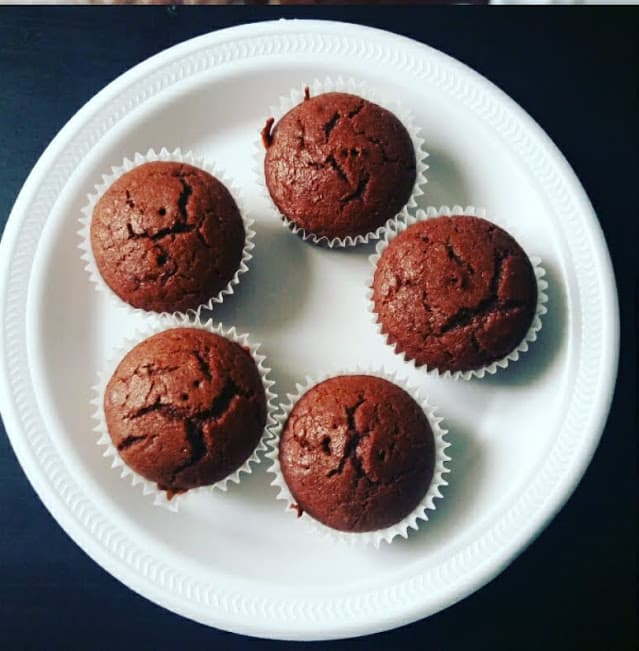 An overhead picture of white plate with 5 chocolate cupcakes