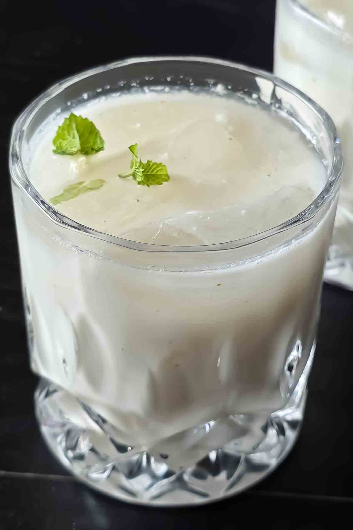 Glass of Indian Spiced Buttermilk garnished with roasted cumin and cilantro.