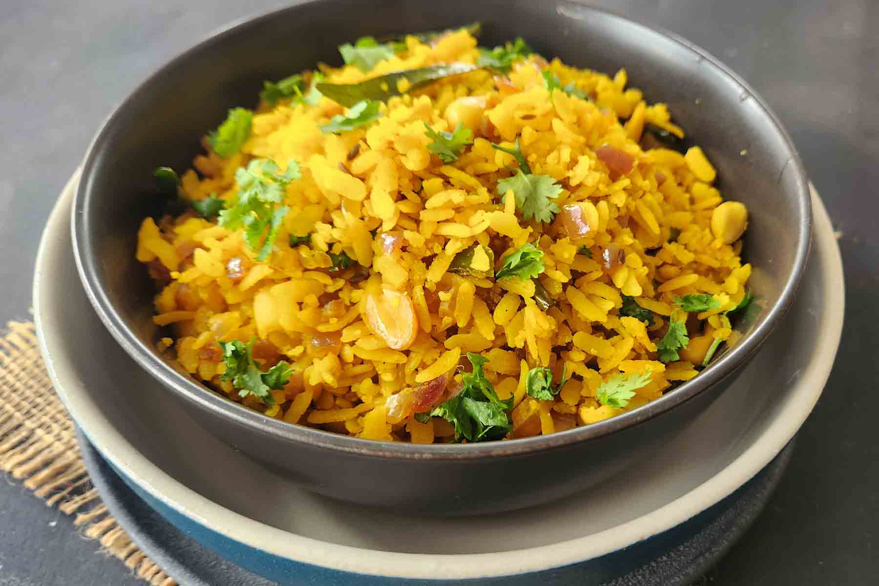 Gluten-free Poha breakfast garnished with cilantro and lemon.