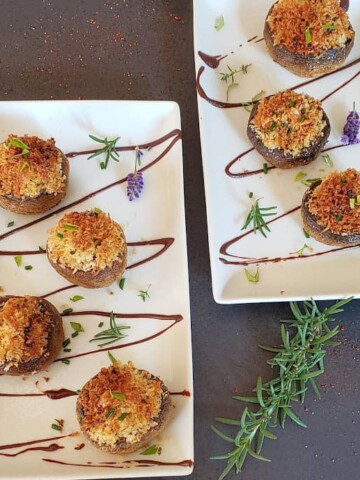 Stuffed mushrooms arranged on two serving platters decorated with herbs and flowers.