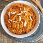 Carrot Almond Pudding is a traditional Indian dessert called Gajar Halwa. It is served in a white bowl with almond garnish.