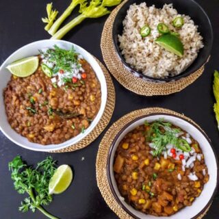 Lentil chili garnished with lemon wedges, cilantro and peppers served with brown rice.