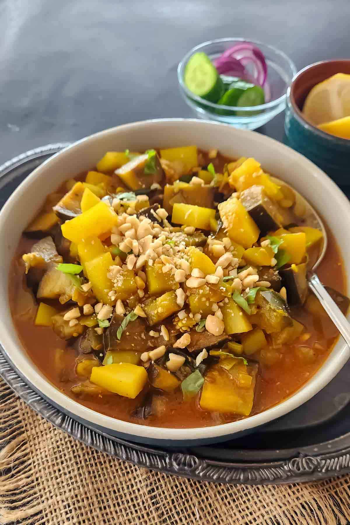 A bowl of Aloo Baingan - Indian curry made with eggplant and potatoes garnished with ground peanuts.