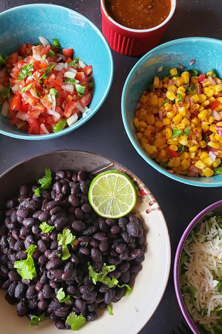 Close up of the bowls full of cuban black beans, corn and salsa.