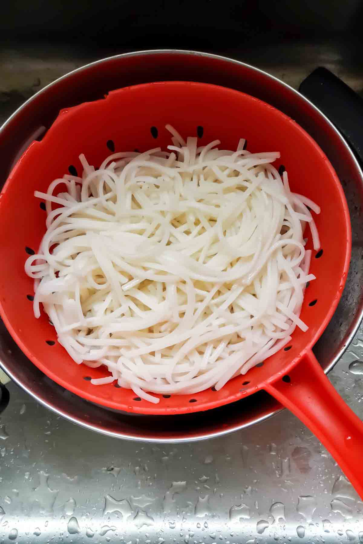 Rice stick noodles cooked in hot water and drained water in colander.
