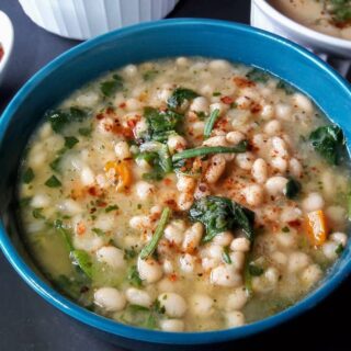 A blue bowl full of vegan White Bean and Spinach Soup made in Instant Pot.