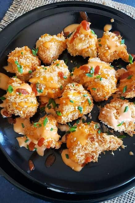 Golden brown and crispy cauliflower bites served with sauce and garnishes.