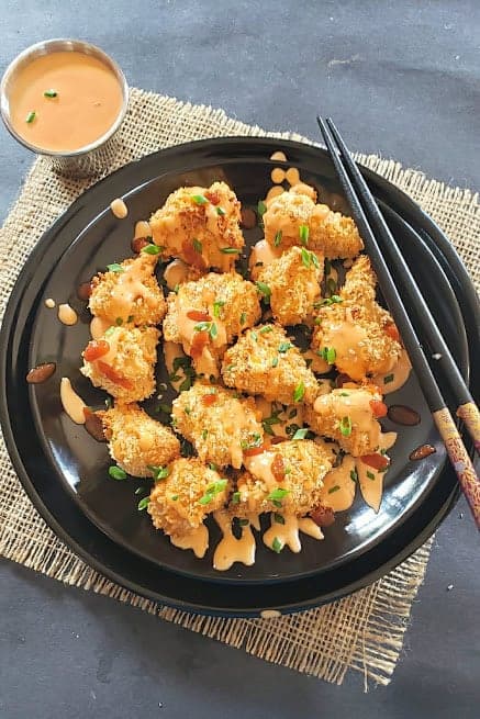 Crispy Cauliflower bites served with sauce and chopsticks.