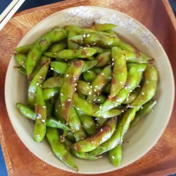 Spicy edamame which are young green soybean pods cooked in spicy chili garlic sauce to make appetizer or snack.