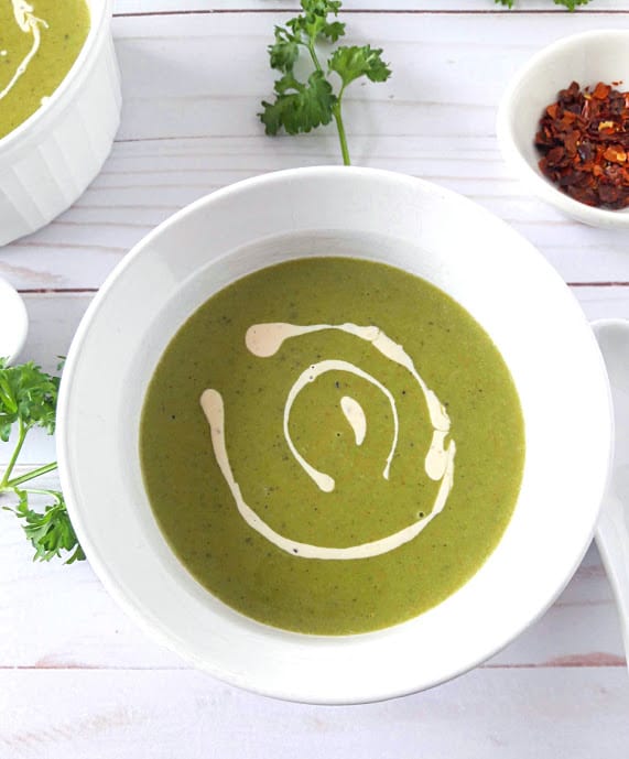 Green Peas and Mint Soup in a bowl with swirl of vegan cashew cream on top