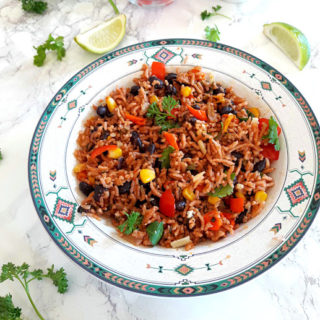 A bowl full of enchilada rice with black beans, corn and spinach cooked in delicious enchilada sauce.