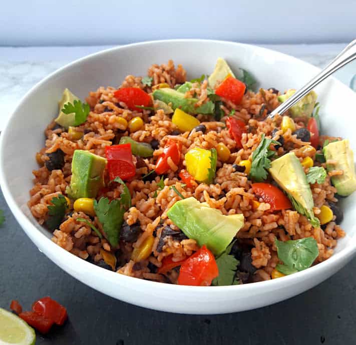 Encilada Rice Bowl with cilantro and avacado slices as garnish with a spoon