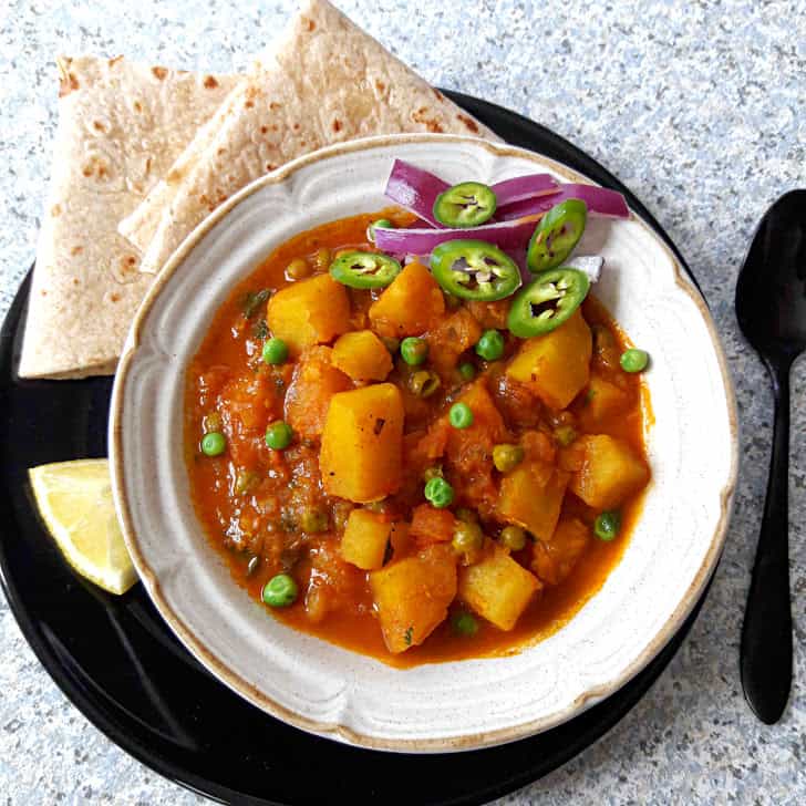 Potato and Peas Curry-Aloo Matar with Roti and onions and lemon wedge