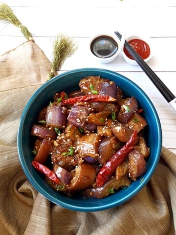 Chinese Spicy Eggplant in blue serving bowl with chop sticks on the side