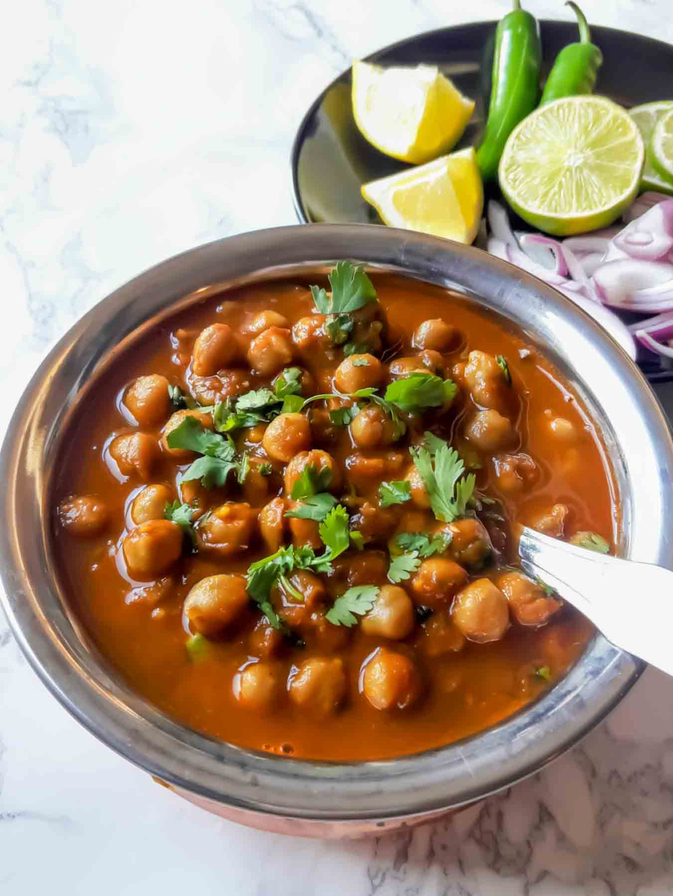 Instant Pot Chole Masala served in a bowl with fresh cilantro and lemon wedges on the side