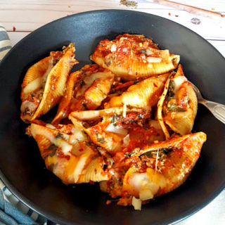 Instant Pot created Stuffed Pasta Shells with spinach, cheese and Italian Seasoning. Pefect weeknight comforting dinner served on black plate with cheese sprinkled on top.