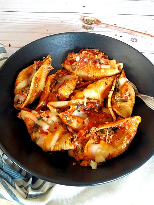 InstantPot created Stuffed Pasta Shells with spinach, cheese and Italian Seasoning. Pefect weeknight comforting dinner served on black plate with cheese sprinkled on top.