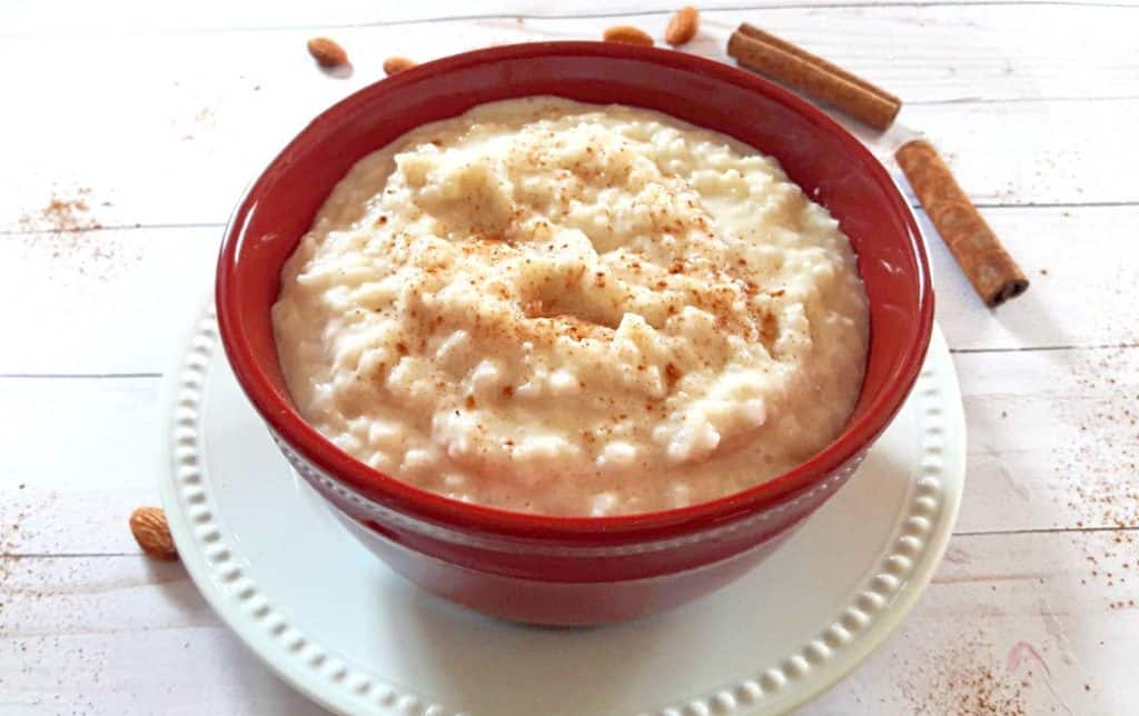 Easy Creamy Rice Pudding served cold in red bowl with cinnamon and nutmeg sprinkle 