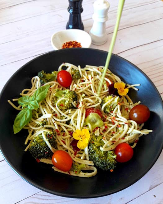 camera shot of Cashew Lemon Basil dressing getting poured over spaghetti and veggies . This delicious dinner recipe is by ProfusionCurry