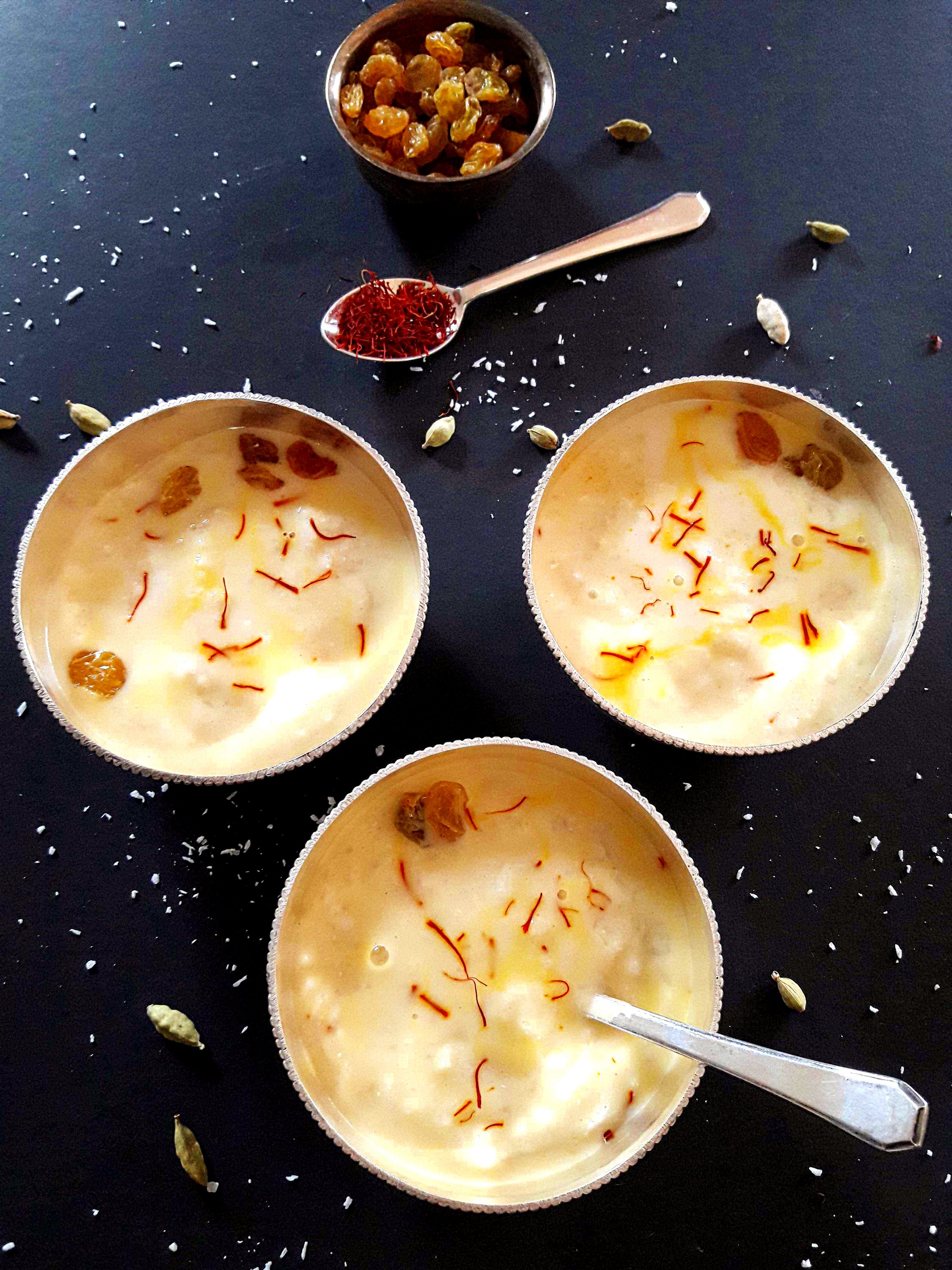 Coconut rice kheer garnished with saffron strands and raisins served in the silver bowls. 