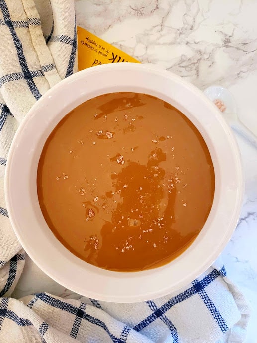 Overhead shot of Instant pot caramel cream served with sea salt crystals on marble countertop.