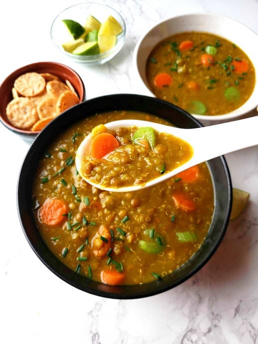 Lentil Quinoa Vegetables Soup with the soup spoon and gluten free crackers for the side.