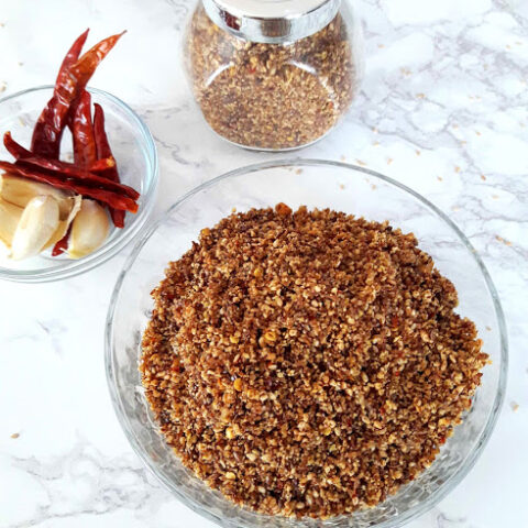 Flaxseed and garlic chutney in glass container and in the mason jar bottle resting on the marble countertop.