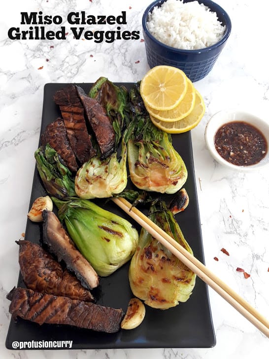 Miso Glazed Grilled Veggies served on black platter with rice and lemon wedges