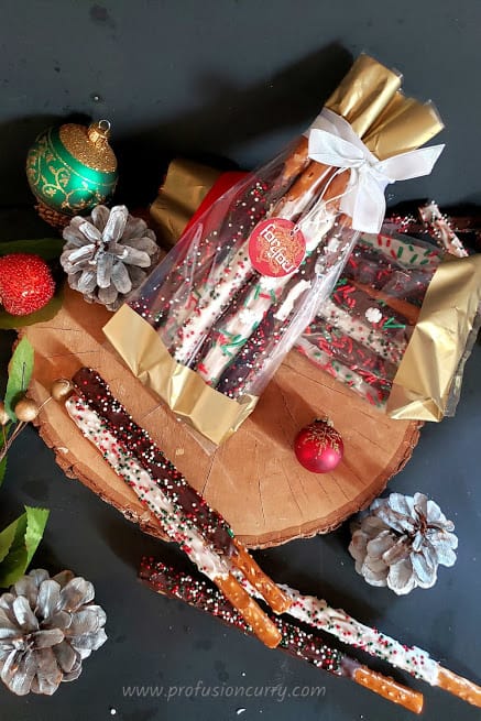 Chocolate dipped holiday pretzels wrapped in gift bags for holiday celebrations.