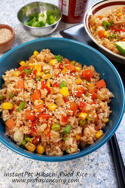 Hibachi Fried Rice served in blue bowl with garnishes and chopsticks.