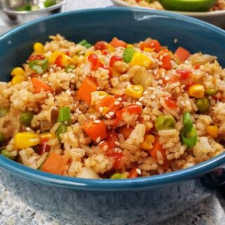 Instant Pot Vegetable Fried rice served in a blue bowl along with sesame seeds and green onions. This fried rice recipe akes best easy meal in one pot.