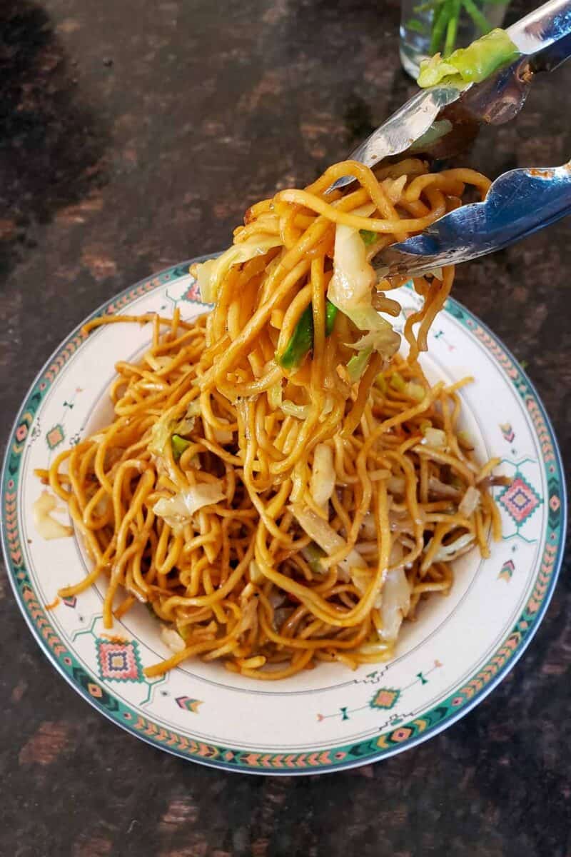 Lo Mein Noodles getting served in a bowl.