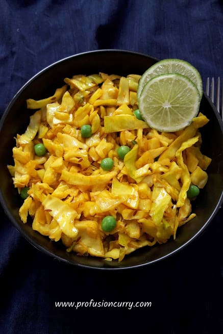 Turmeric Cabbage and peas stir-fry served in a bowl with two lime wedges for garnish.