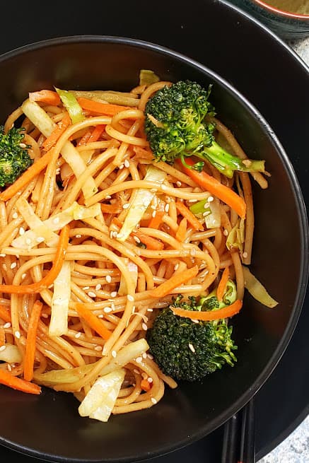 Close up image of Instantpot Lo Mein Noodles showing soft and moist texture. These noodles are cooked with colorful veggies and are garnished with sesame seeds.