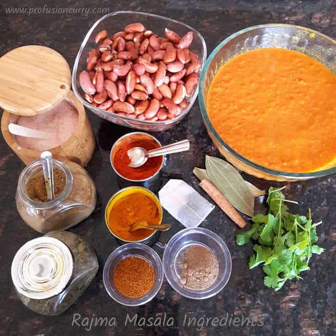 all the ingredients needed to make Rajma Curry gathered around on black granite countertop.