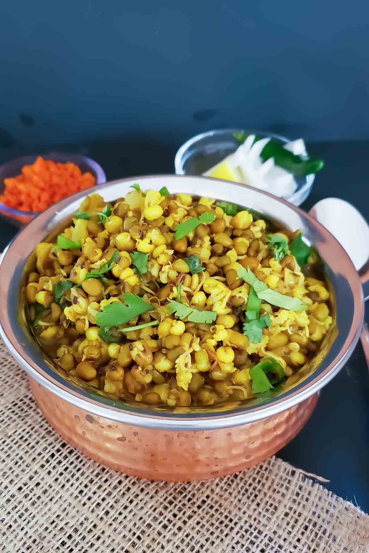Bowl of healthy green moong sprouts curry garnished with fresh cilantro.