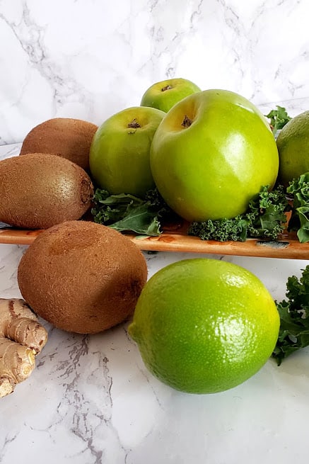 Ingredients used in raw green superffod smoothie displayed on white marble countertop.