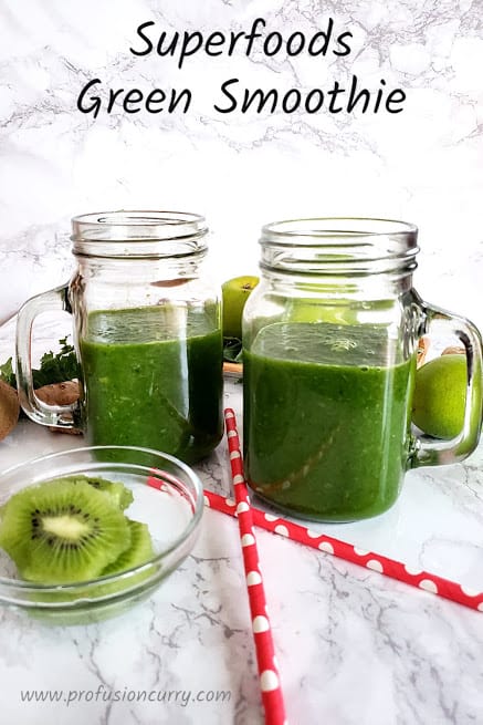 Dos frascos de vidrio albañil rellenos de Batido Verde Crudo. Dos pajitas rosadas a un lado para beberlo. Un par de rodajas de kiwi para el munchin.