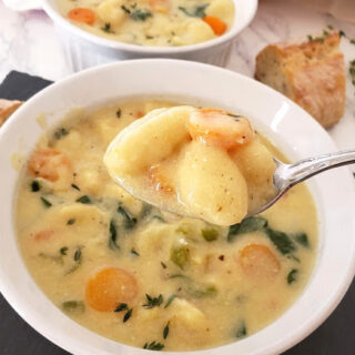 A spoonful of creamy soup and gnocchi showing creamy and hearty texture of delicious soup recipe.