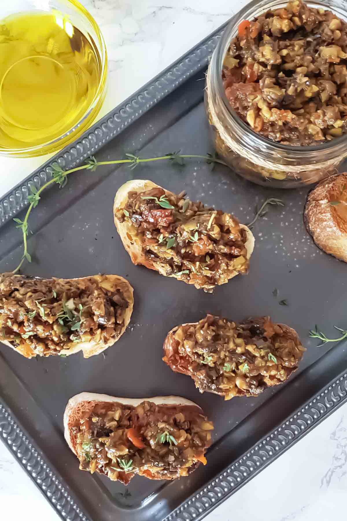 An appetizer tray full of toasts topped with homemade olive tapenade recipe.