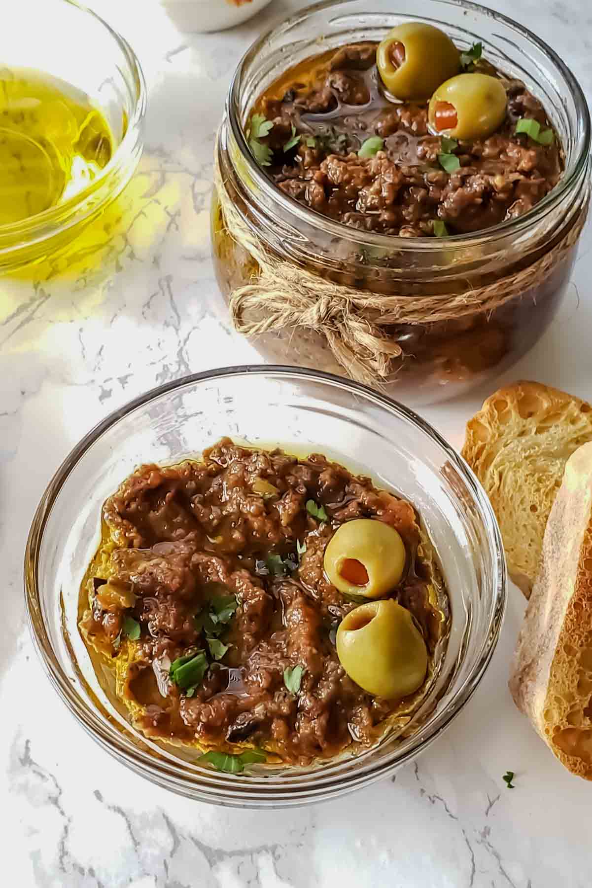 A bowl and a jar filled with homemade olive tapenade without anchovies recipe. 
