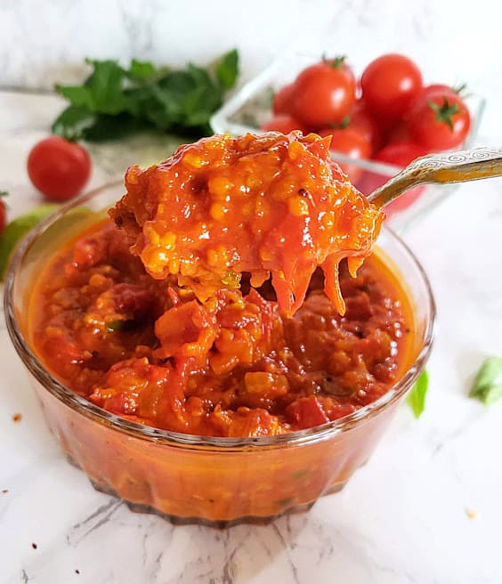 a spoon scooping the tomato chuney for serving.