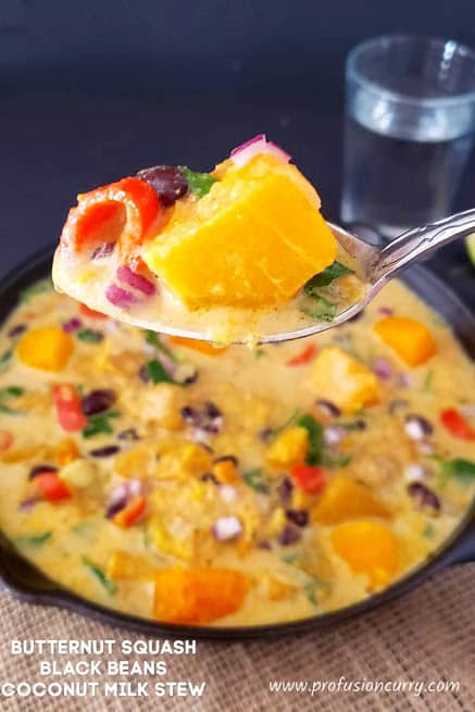 A spoonful of stew scooped from the serving of creamy Butternut squash stew. Showing creamy texture and colorful ingredients.