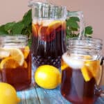 Close up image of a glass pitcher and two glass mason jar full of Iced Tea